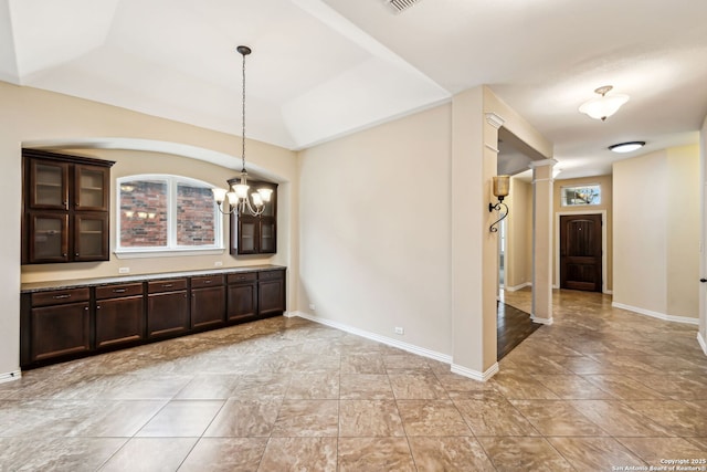 unfurnished dining area with decorative columns and a notable chandelier