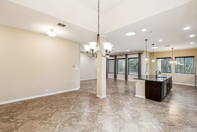 kitchen featuring decorative light fixtures, sink, dark brown cabinetry, and a notable chandelier