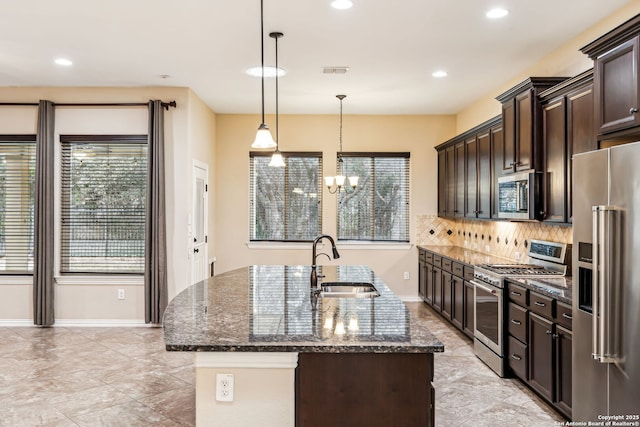 kitchen with appliances with stainless steel finishes, decorative light fixtures, dark stone counters, dark brown cabinetry, and sink