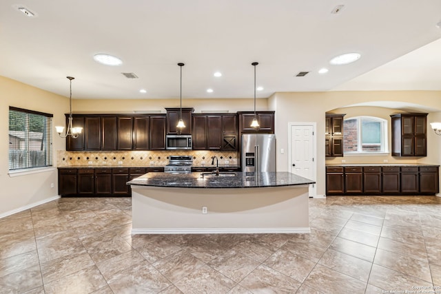 kitchen with decorative light fixtures, dark stone counters, sink, and stainless steel appliances