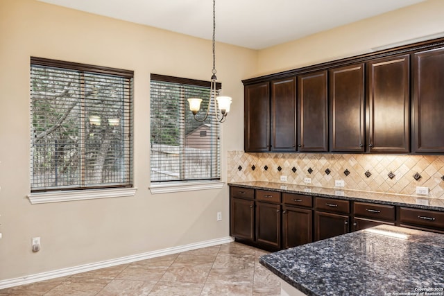 kitchen with decorative backsplash, dark brown cabinets, dark stone counters, and pendant lighting