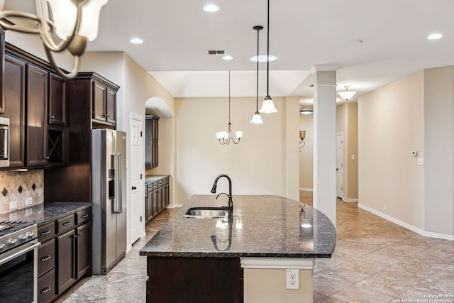 kitchen featuring appliances with stainless steel finishes, tasteful backsplash, a kitchen island with sink, dark brown cabinets, and sink