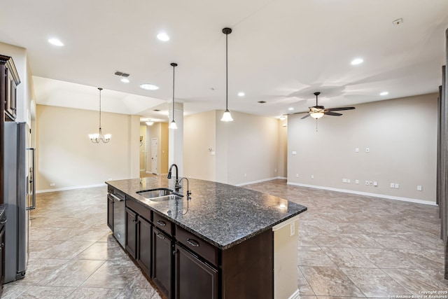 kitchen featuring sink, dark brown cabinets, dark stone countertops, and decorative light fixtures