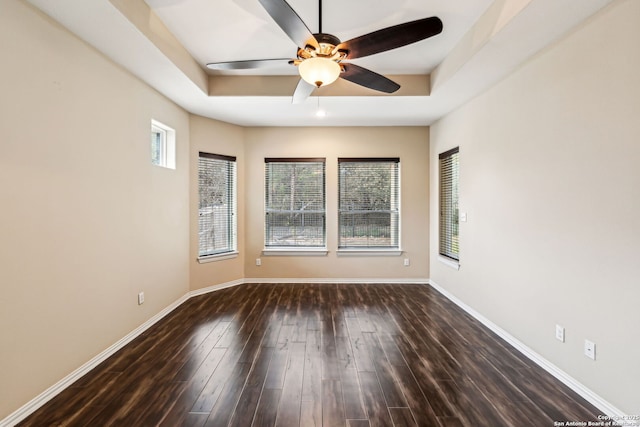 spare room featuring a raised ceiling, ceiling fan, and dark wood-type flooring