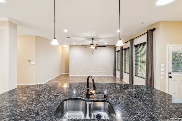 kitchen with ceiling fan, sink, pendant lighting, and dark stone counters