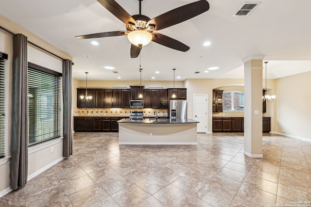 kitchen with stainless steel appliances, backsplash, a kitchen island with sink, pendant lighting, and sink