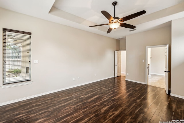 unfurnished room with ceiling fan, dark hardwood / wood-style flooring, and a tray ceiling