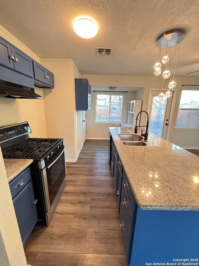 kitchen featuring a textured ceiling, gas stove, decorative light fixtures, sink, and blue cabinetry