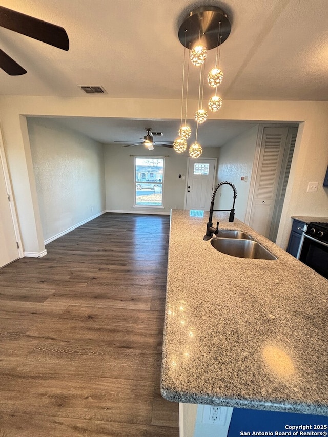 kitchen with a center island with sink, sink, and pendant lighting