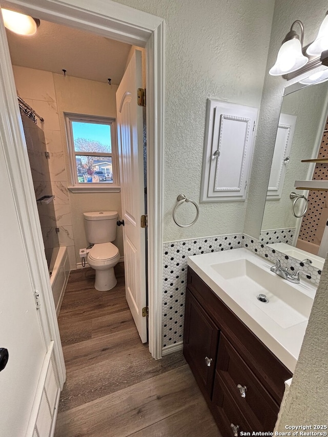 full bathroom featuring toilet, tiled shower / bath, hardwood / wood-style floors, and vanity