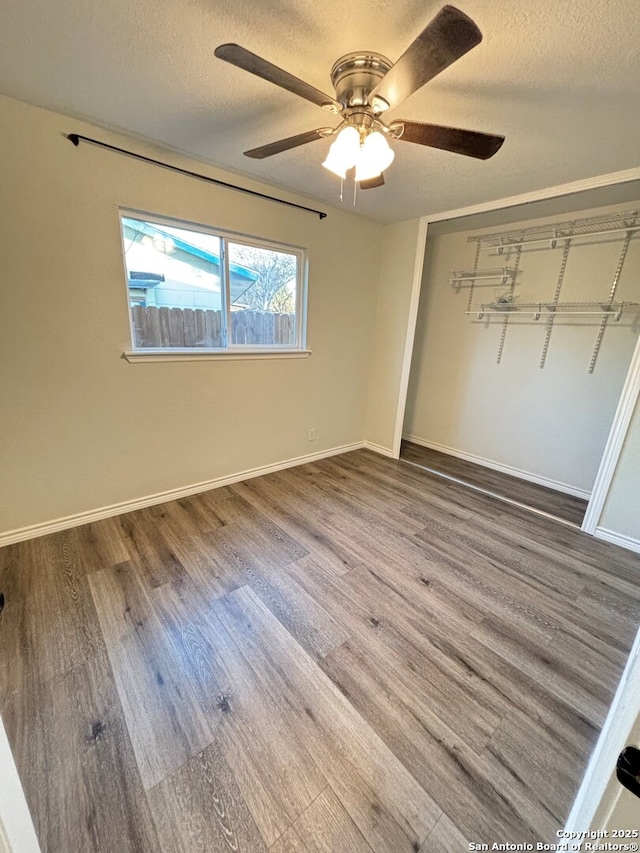 unfurnished bedroom with a textured ceiling, ceiling fan, a closet, and wood-type flooring