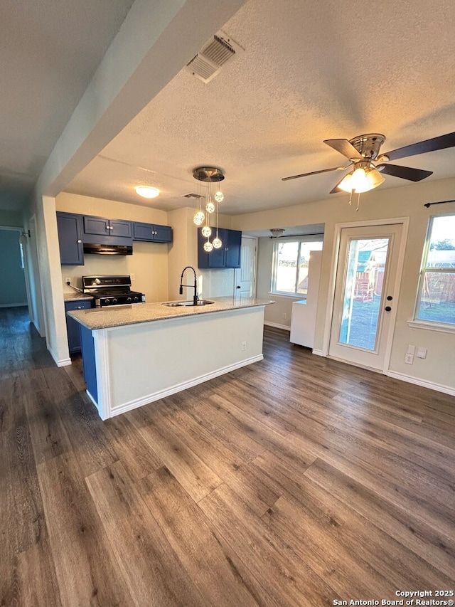 kitchen featuring gas stove, dark hardwood / wood-style floors, hanging light fixtures, and sink