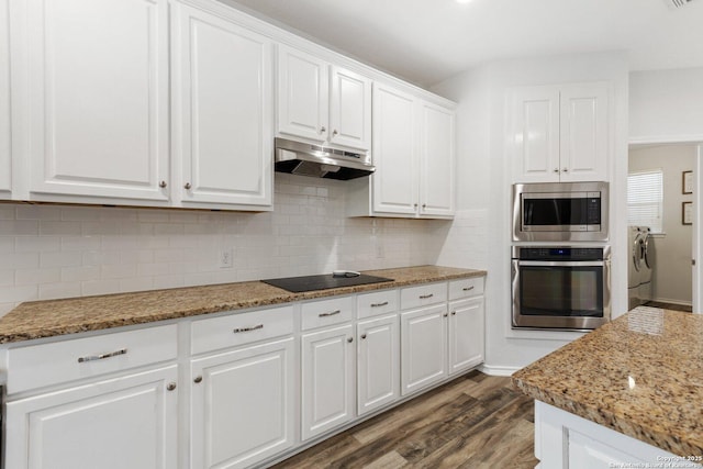 kitchen with decorative backsplash, appliances with stainless steel finishes, white cabinetry, washer / dryer, and under cabinet range hood