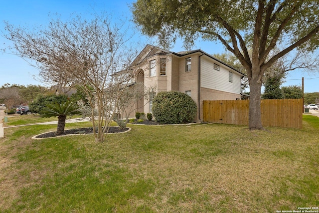 view of side of property featuring fence, a lawn, and brick siding