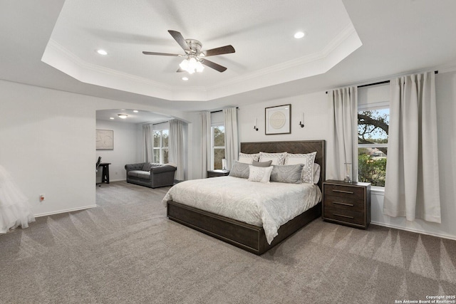 carpeted bedroom with a ceiling fan, baseboards, a raised ceiling, and crown molding