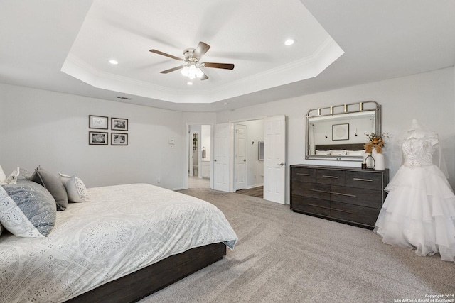 carpeted bedroom featuring a ceiling fan, ornamental molding, ensuite bathroom, a tray ceiling, and recessed lighting