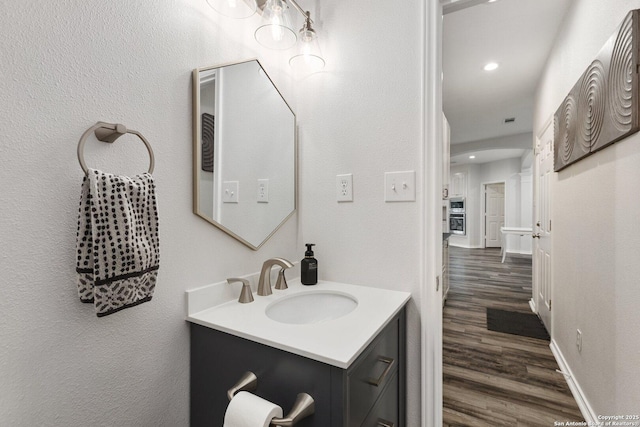 bathroom featuring recessed lighting, baseboards, wood finished floors, and vanity