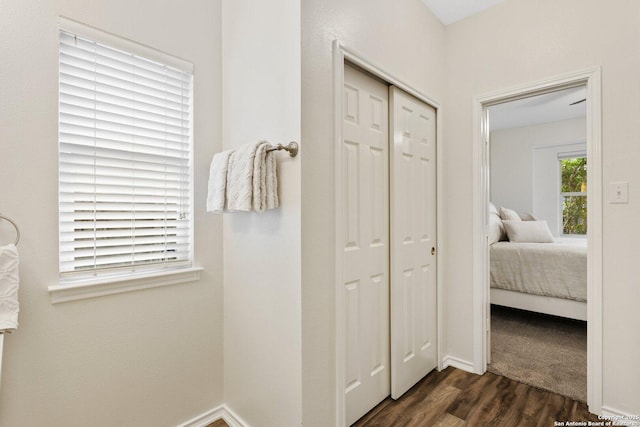 corridor with dark wood-style floors and baseboards