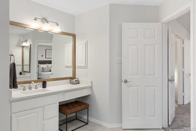 bathroom with baseboards, vanity, and ensuite bath