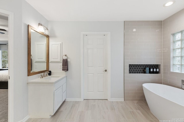 ensuite bathroom with a soaking tub, baseboards, vanity, and ensuite bath