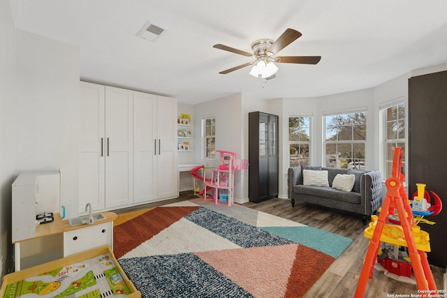 playroom with visible vents, ceiling fan, and wood finished floors