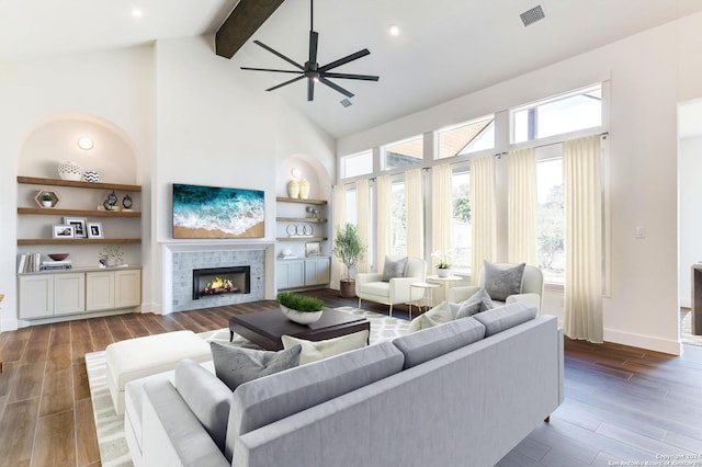 living room featuring built in features, a fireplace, a high ceiling, and beamed ceiling