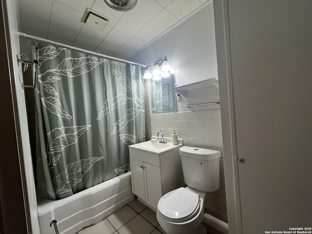 full bathroom with toilet, shower / bath combo with shower curtain, tile walls, tile patterned floors, and vanity