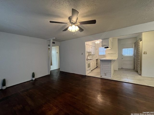 unfurnished living room featuring ceiling fan, a textured ceiling, and light hardwood / wood-style floors