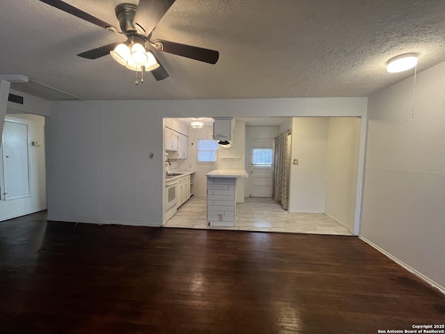 unfurnished living room featuring a textured ceiling, ceiling fan, light hardwood / wood-style floors, and sink