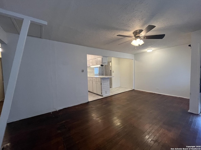 unfurnished living room featuring ceiling fan, hardwood / wood-style floors, and a textured ceiling