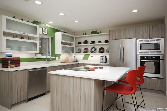 kitchen featuring appliances with stainless steel finishes, a center island, a kitchen breakfast bar, light tile patterned flooring, and sink