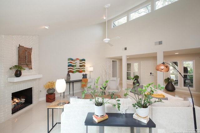 tiled living room featuring ceiling fan, a fireplace, and a towering ceiling