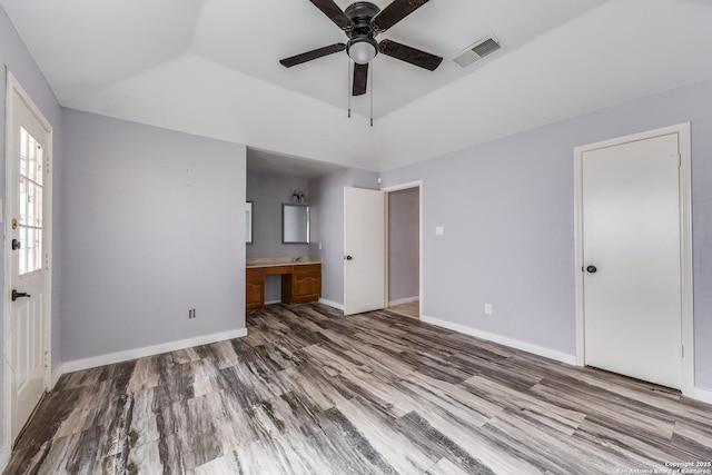 unfurnished living room with hardwood / wood-style flooring, built in desk, ceiling fan, and a raised ceiling