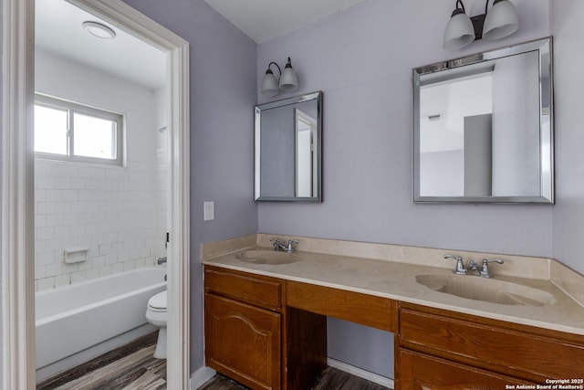 full bathroom with hardwood / wood-style floors, toilet, vanity, and tiled shower / bath