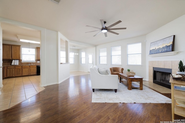 living room featuring ceiling fan, a tile fireplace, and light hardwood / wood-style flooring