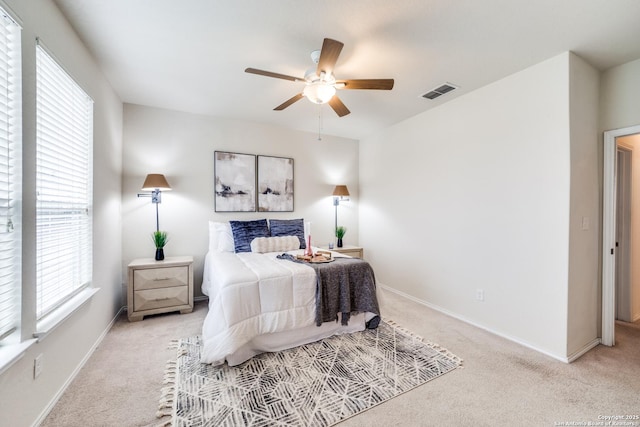 carpeted bedroom featuring ceiling fan and multiple windows