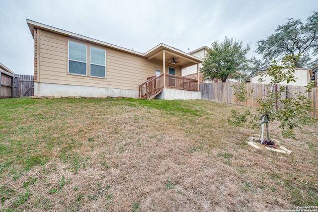 rear view of property with a lawn and ceiling fan