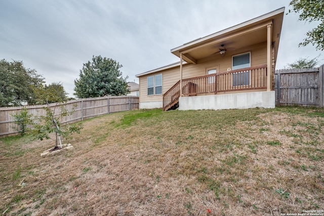 back of house featuring ceiling fan, a deck, and a lawn