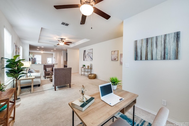 office area featuring plenty of natural light, light colored carpet, and a tray ceiling