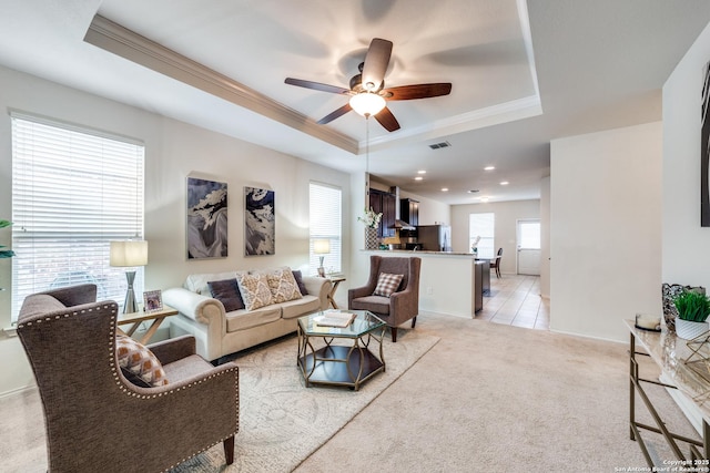 living room featuring ceiling fan, light colored carpet, and a tray ceiling