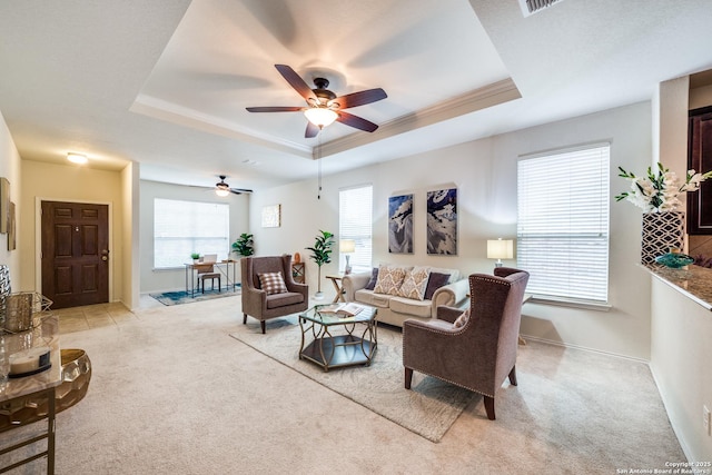 living room with light colored carpet, crown molding, and a tray ceiling