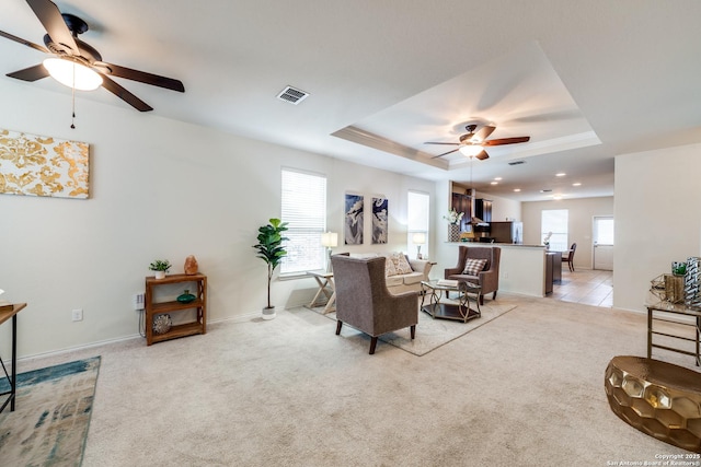 carpeted living room featuring ceiling fan and a raised ceiling