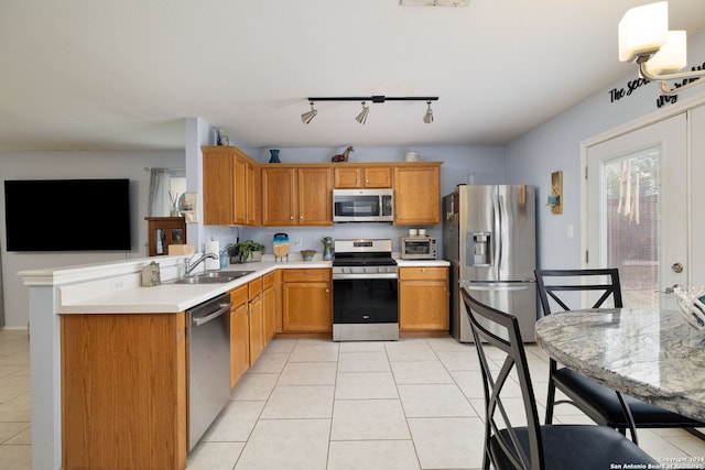 kitchen featuring stainless steel appliances, sink, rail lighting, kitchen peninsula, and light tile patterned flooring