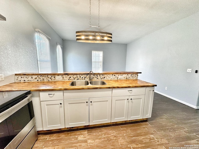 kitchen with decorative light fixtures, white cabinetry, and wooden counters