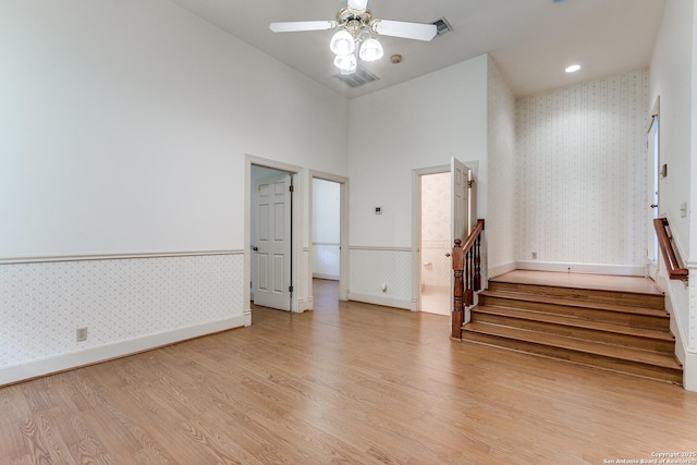 spare room featuring ceiling fan, light hardwood / wood-style flooring, and a towering ceiling