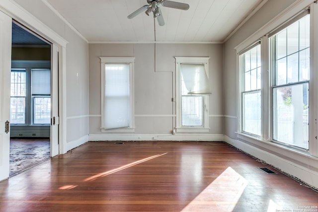 unfurnished room featuring a wealth of natural light, dark hardwood / wood-style floors, and crown molding