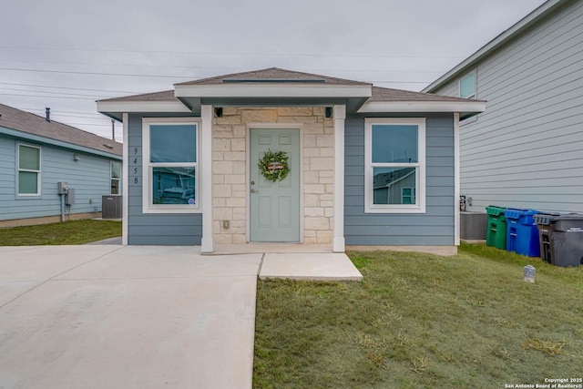 entrance to property with a lawn and cooling unit