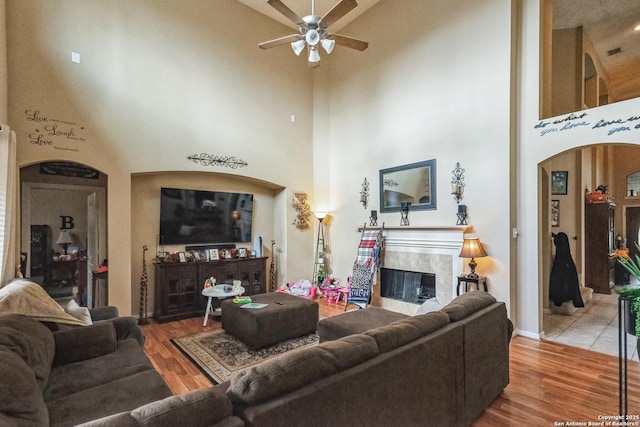 living room featuring hardwood / wood-style floors, a towering ceiling, and a fireplace