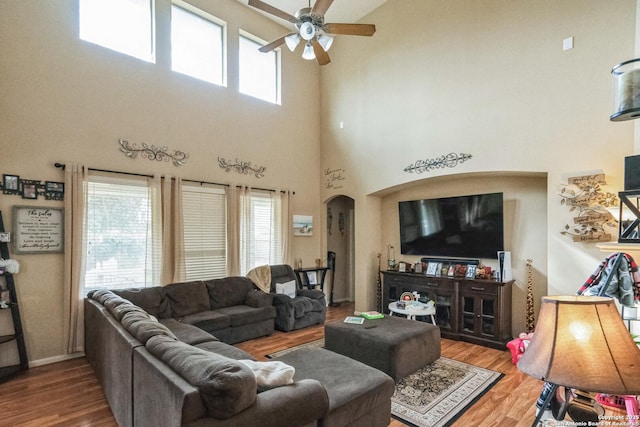 living room featuring a high ceiling, hardwood / wood-style flooring, and ceiling fan