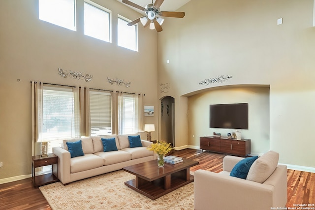 living room with a high ceiling, wood-type flooring, and ceiling fan